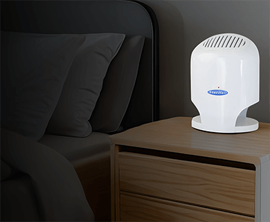 Purificador de ar Sterilair branco sobre o criado-mudo, ao lado da cama